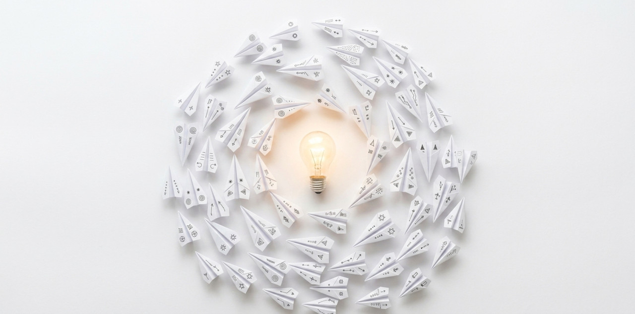many paper airplanes flying in a circular formation around a central glowing light bulb