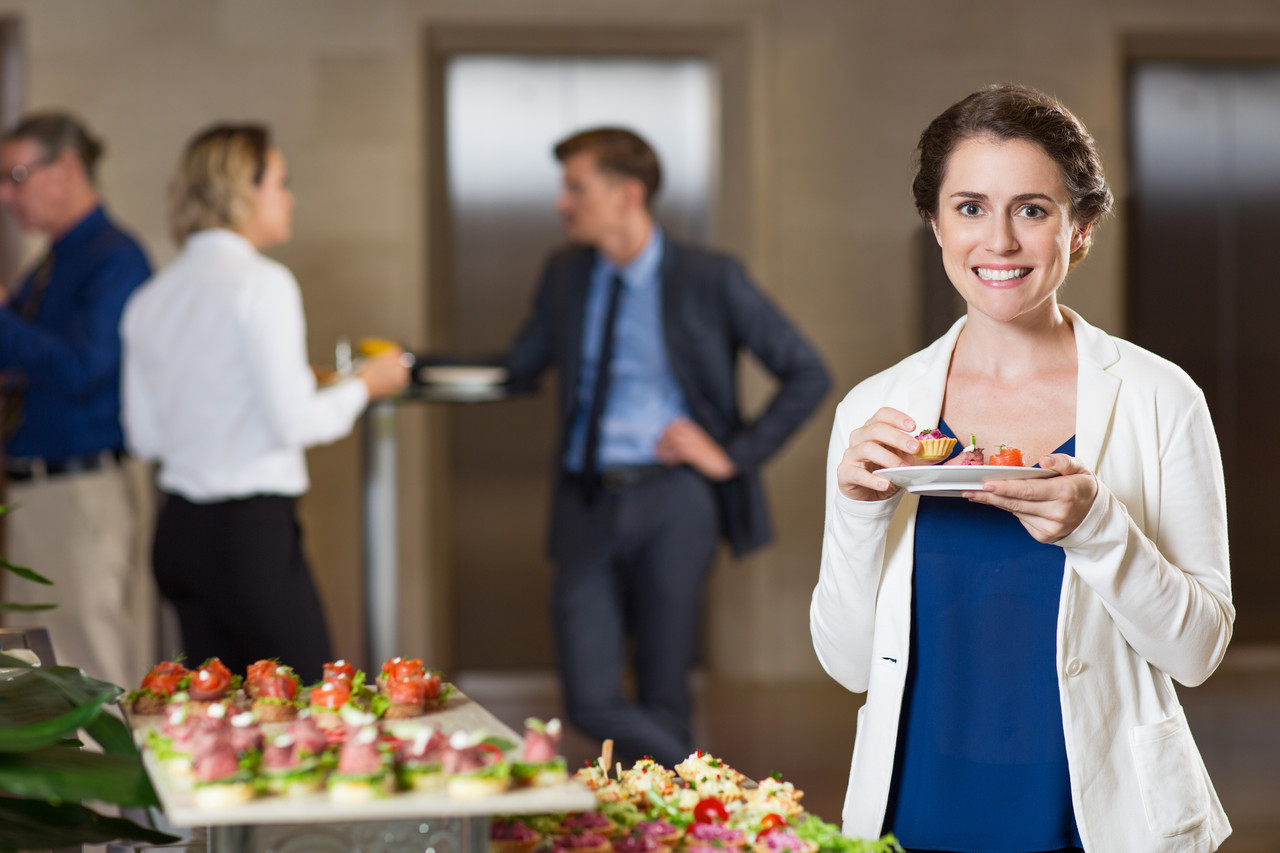 smiling woman eating snacks buffet reception
