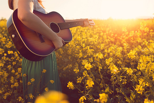 women playing a guitar in field of flowers
