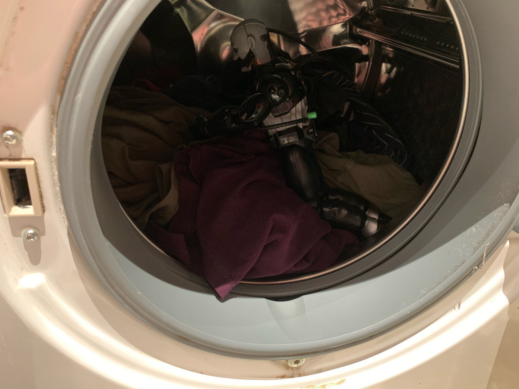 Black robot helping to Load in the dirty clothes into the washing machine. 7-C8-E76-FB-9534-453-E-A741-CA48-FBC443-B5