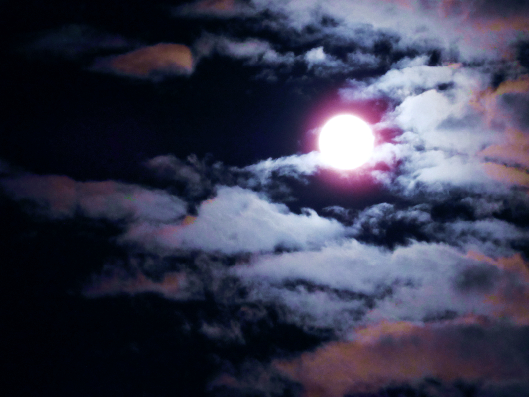 a photograph of the full moon surrounded by clouds