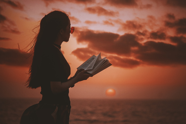 Young-girl-posing-with-book-on-sea-sunset-Stock-Photo.jpg