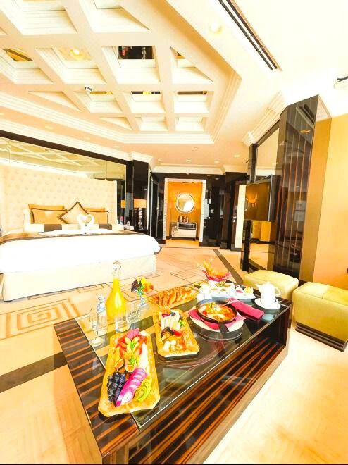 غرفة فاخرة في فندق Mövenpick Grand Al Bustan Dubai، تضم سريرًا ملكيًا أنيقًا، ومساحة واسعة بديكور دافئ يعكس الفخامة السويسرية والضيافة العربية