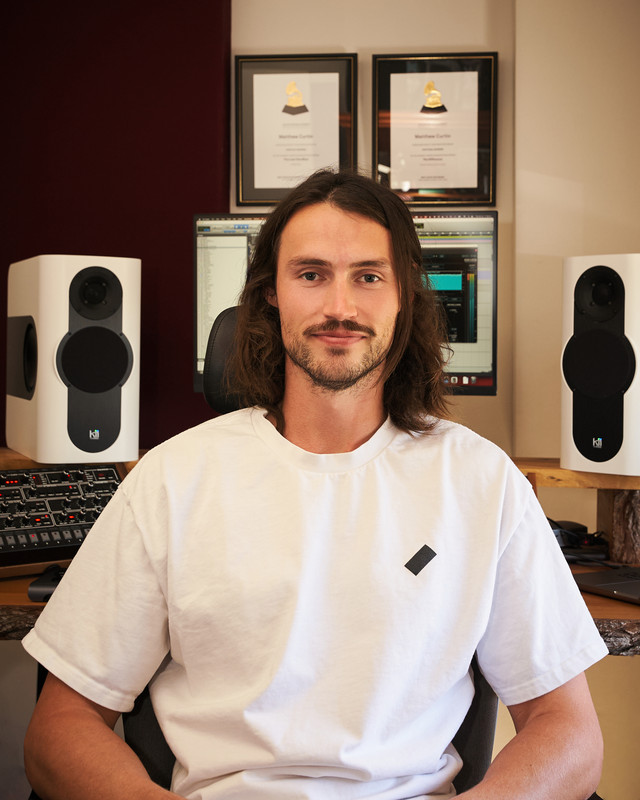 A professional music production studio with mixing board and speakers.