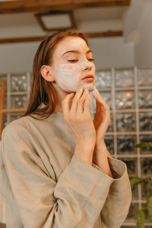 a younge woman washing her face with harsh, foaming cleanser that will remove her skin's natural oils and harm her skin barrier. 