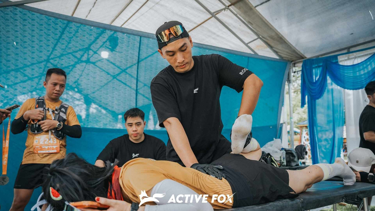 Kỹ thuật viên Active Fox massage kéo giãn chân cho runner ngay sau giải chạy để phục hồi cơ