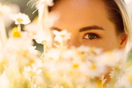 151783823-portrait-of-a-sunny-woman-embracing-a-bunch-of-chamomile-with-the-sun-rays-on-her-face-enj.jpg