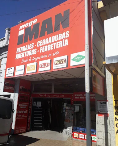 Fachada local Mega Imán en Rivadavia 480 Córdoba. Cartel rojo con logo. Texto: Herrajes, Cerraduras, Aberturas, Ferretería. Frase: Desde la trayectoria se nota. Distribuidores oficiales marcas Currao, Kallay, Prive.