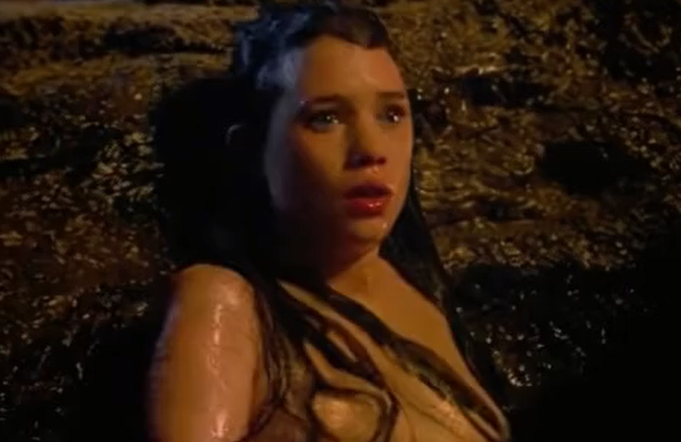 A sexy girl is sitting in the water and showing her boobs.